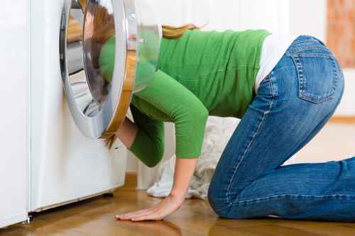 Frau schaut in defekte Waschmaschine